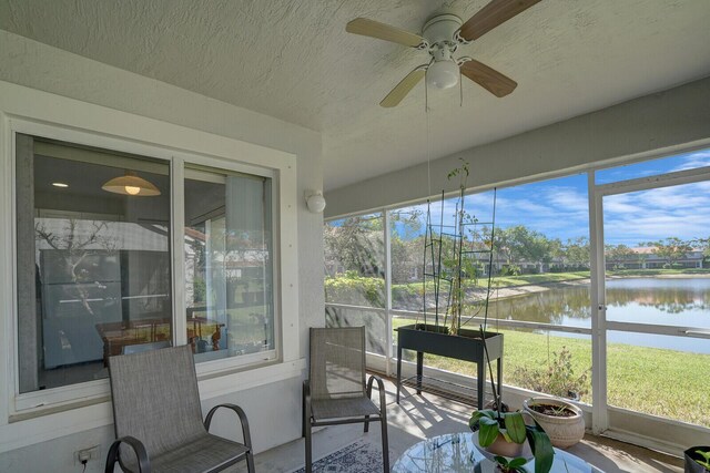 sunroom / solarium with a water view and a ceiling fan