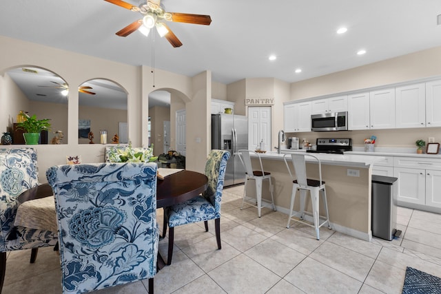 dining space with light tile patterned floors, arched walkways, ceiling fan, and recessed lighting