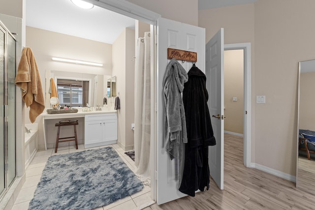 bathroom with vanity, wood finished floors, baseboards, a stall shower, and a bath