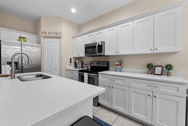 kitchen featuring light tile patterned floors, appliances with stainless steel finishes, white cabinetry, and a sink