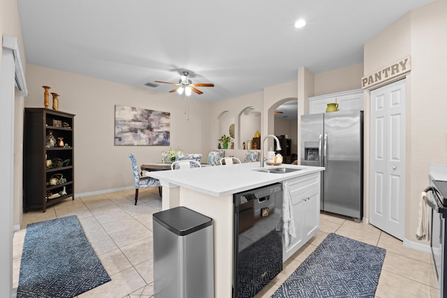 kitchen featuring a center island with sink, appliances with stainless steel finishes, arched walkways, white cabinets, and a sink