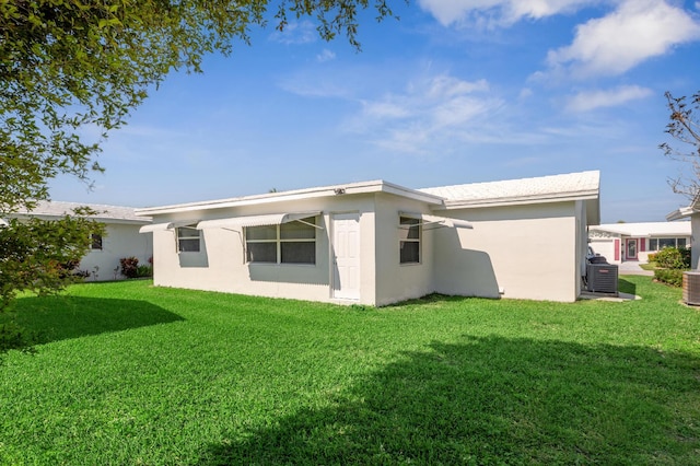 back of property featuring a lawn, cooling unit, and stucco siding