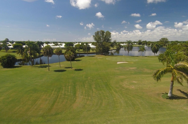 view of property's community featuring golf course view, a lawn, and a water view