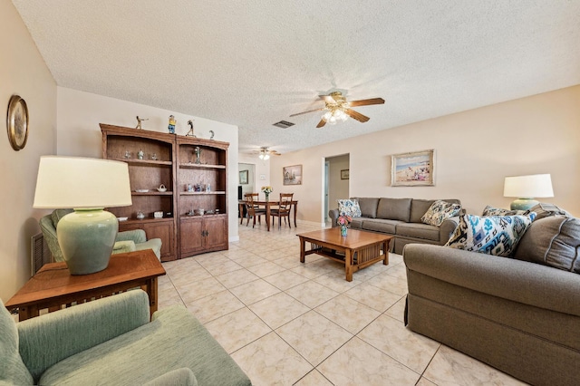 living area featuring light tile patterned floors, visible vents, a textured ceiling, and ceiling fan