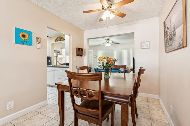 dining space featuring a textured ceiling, light tile patterned floors, baseboards, and ceiling fan