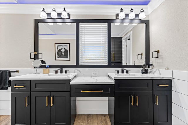 bathroom featuring ornamental molding, wood finished floors, two vanities, and a sink