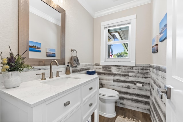 bathroom with toilet, ornamental molding, wood finished floors, wainscoting, and vanity