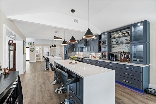 kitchen with visible vents, a center island with sink, lofted ceiling, custom range hood, and stainless steel appliances