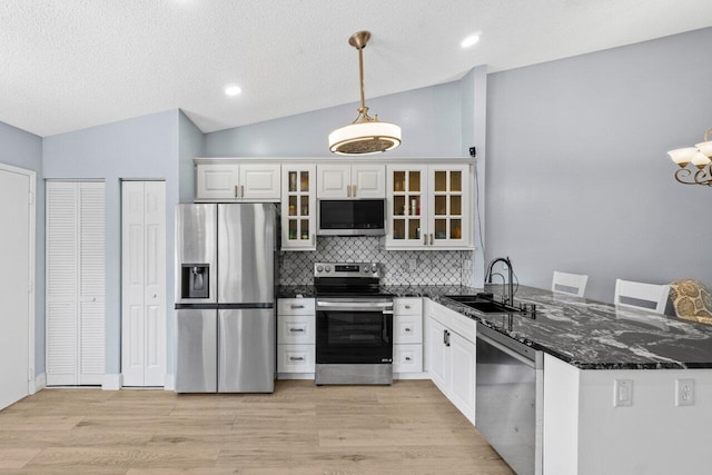 kitchen with light wood-style flooring, a sink, appliances with stainless steel finishes, glass insert cabinets, and lofted ceiling