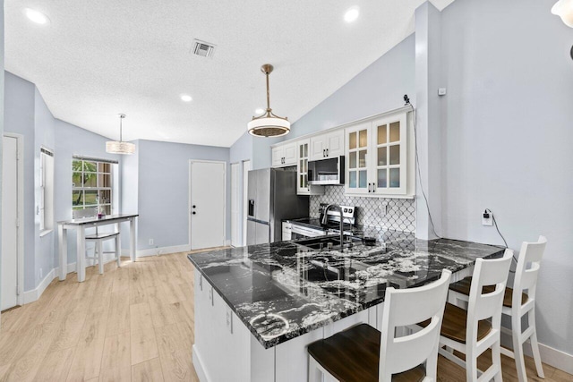 kitchen featuring visible vents, a sink, decorative backsplash, glass insert cabinets, and appliances with stainless steel finishes