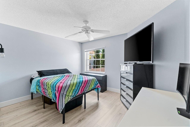 bedroom featuring ceiling fan, a textured ceiling, baseboards, and light wood-style floors