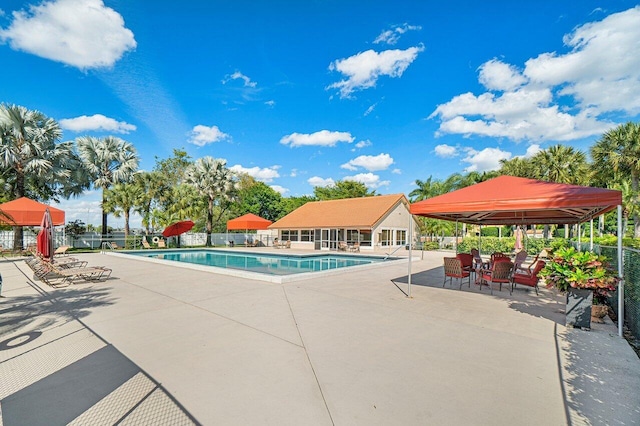 community pool with a patio area, a gazebo, and fence