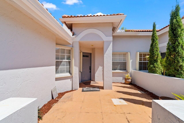 doorway to property featuring stucco siding and a tile roof