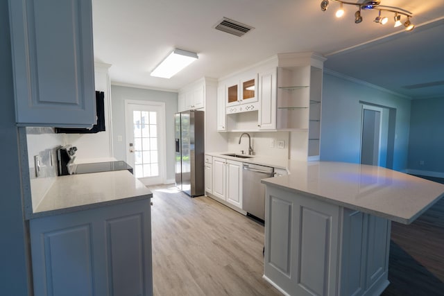 kitchen featuring visible vents, ornamental molding, a sink, appliances with stainless steel finishes, and a peninsula