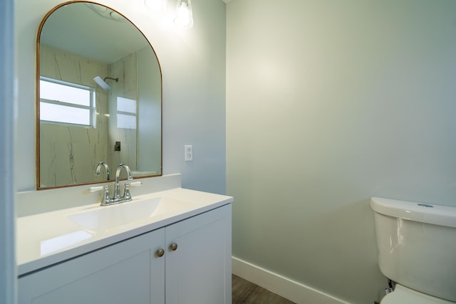 bathroom with baseboards, toilet, wood finished floors, and vanity