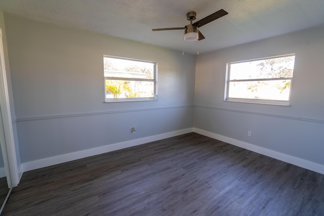 spare room featuring a healthy amount of sunlight, baseboards, and dark wood-style flooring