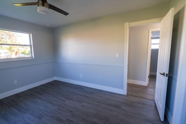empty room with dark wood-style floors, baseboards, and ceiling fan
