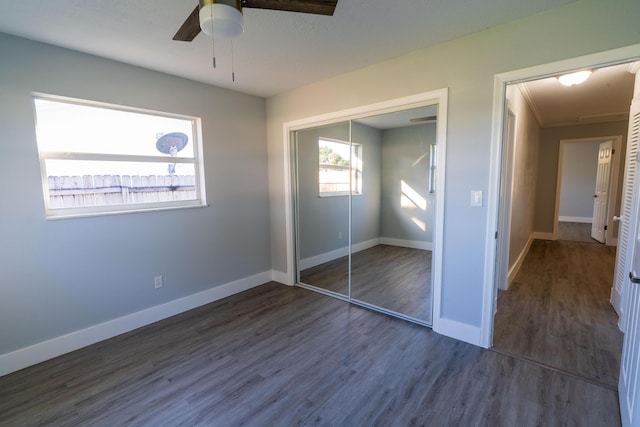 unfurnished bedroom featuring a closet, dark wood-type flooring, and baseboards