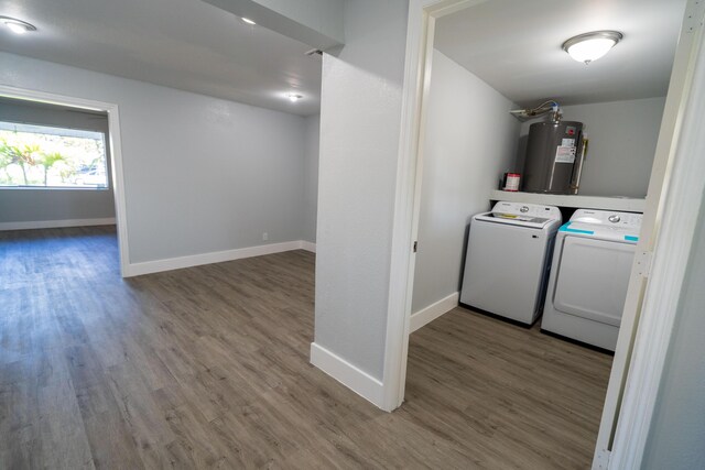 laundry area featuring washing machine and clothes dryer, electric water heater, baseboards, laundry area, and wood finished floors