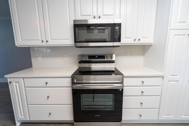kitchen with wood finished floors, stainless steel appliances, light countertops, white cabinetry, and backsplash