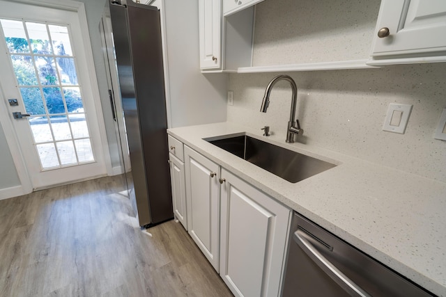 kitchen with stainless steel appliances, light wood-style floors, plenty of natural light, white cabinetry, and a sink