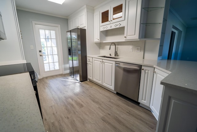 kitchen with white cabinets, ornamental molding, appliances with stainless steel finishes, and a sink