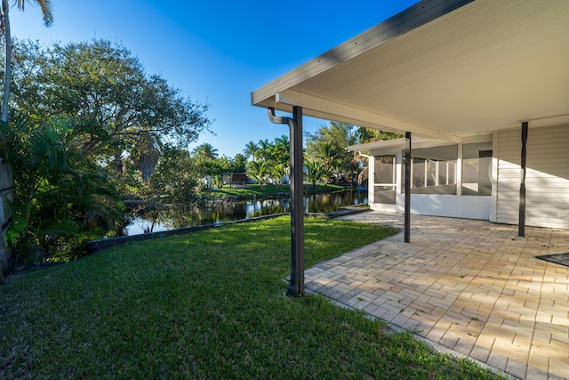 view of yard with a patio area, a sunroom, and a water view