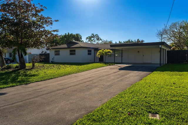 single story home featuring an attached carport, concrete driveway, a front yard, and fence