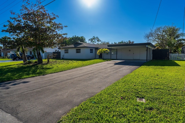 ranch-style house with an attached carport, driveway, a front yard, and fence