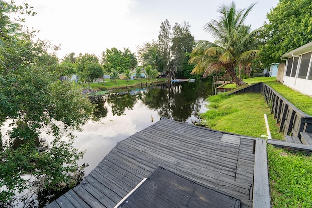 dock area with a water view and a lawn