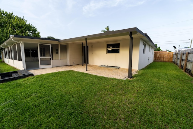 rear view of property with a patio area, a sunroom, a lawn, and a fenced backyard