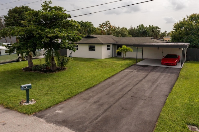 single story home featuring a carport, stucco siding, driveway, and a front yard