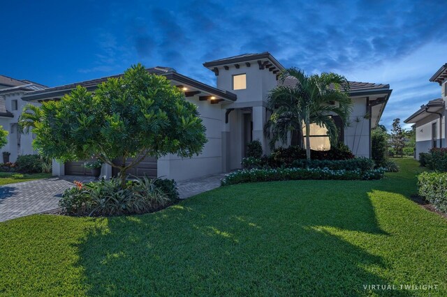 view of front of house with decorative driveway, stucco siding, and a front yard