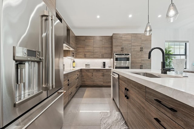 kitchen featuring light tile patterned flooring, a sink, hanging light fixtures, stainless steel appliances, and backsplash