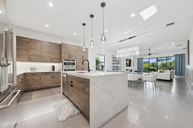 kitchen with open floor plan, light tile patterned floors, brown cabinets, modern cabinets, and a sink