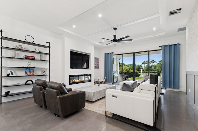 living area featuring visible vents, coffered ceiling, a glass covered fireplace, and a ceiling fan