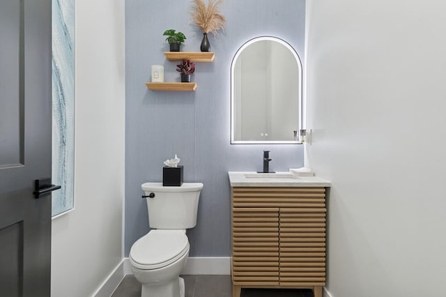 half bathroom with baseboards, toilet, and vanity