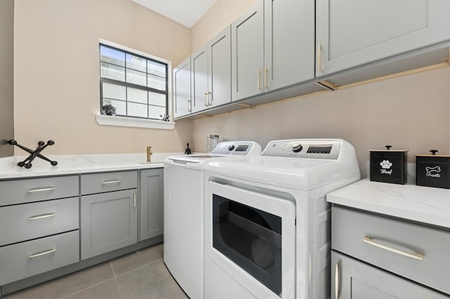 clothes washing area featuring light tile patterned floors, cabinet space, and washing machine and clothes dryer