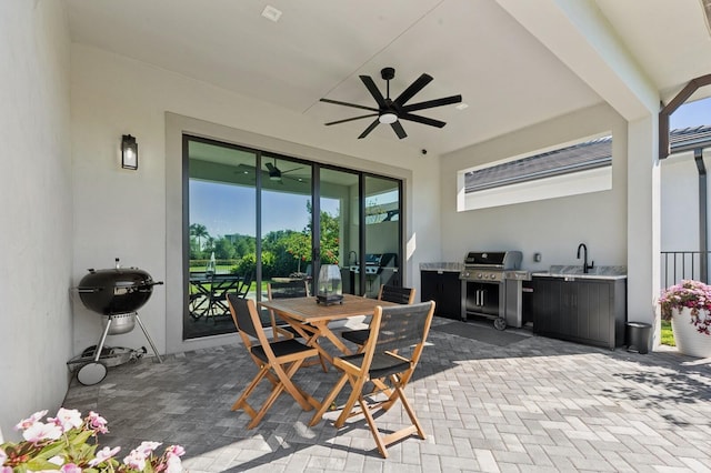 view of patio / terrace with an outdoor kitchen, a grill, outdoor dining space, and a ceiling fan