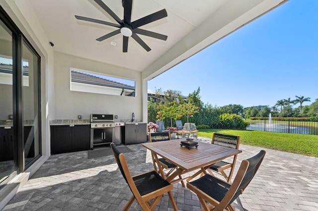 view of patio featuring a ceiling fan, fence, an outdoor kitchen, outdoor dining area, and a grill