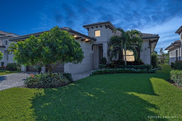 mediterranean / spanish home featuring stucco siding, a front lawn, a tile roof, decorative driveway, and an attached garage