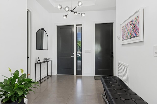 tiled foyer entrance with a notable chandelier and visible vents