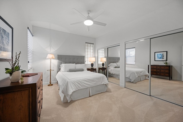 bedroom featuring multiple closets, baseboards, light carpet, and a ceiling fan