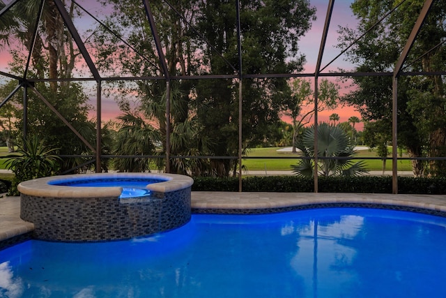 pool at dusk with a pool with connected hot tub and a lanai