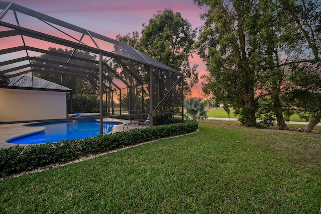 yard at dusk featuring glass enclosure, a patio, and an outdoor pool