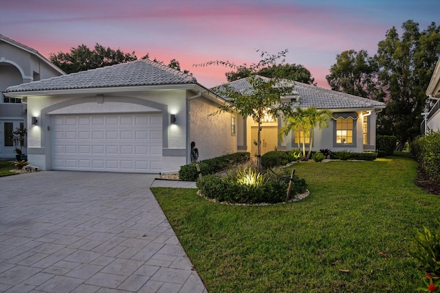 single story home featuring a garage, stucco siding, a tiled roof, a yard, and driveway