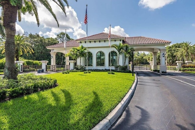 exterior space with fence, a gate, a front yard, and stucco siding