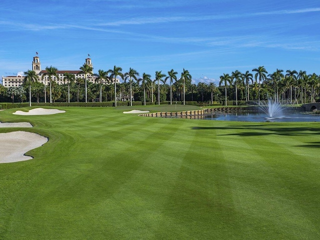 view of community featuring a lawn, view of golf course, and a water view