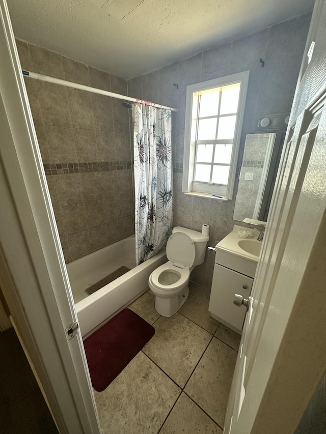 bathroom featuring tile patterned floors, toilet, a textured ceiling, tiled shower, and vanity