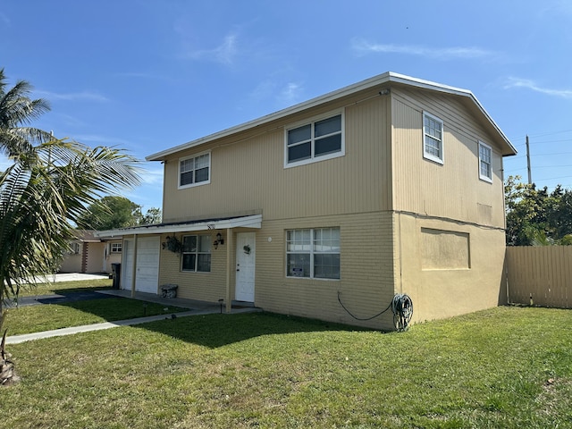 view of front of house featuring brick siding, a front yard, and fence